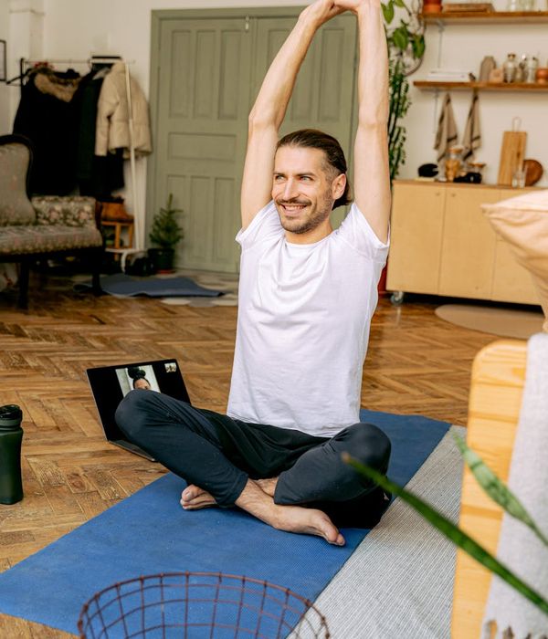 A person stretching gently by their desk, looking relaxed and comfortable.